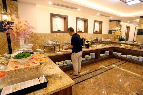 Ein Mann steht vor einem Buffet mit Essen. in der Unterkunft Silk River Hotel Ha Giang in Ha Giang