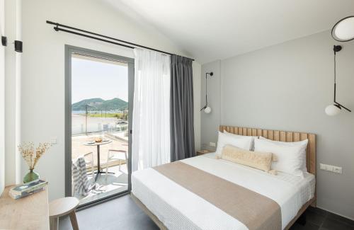 a bedroom with a large bed and a balcony at Yuka Villas Collection in Iraklitsa