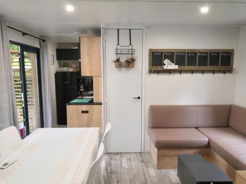 Mobil Home camping 5 étoiles Biscarrosse في بيسكاروس: غرفة معيشة صغيرة مع أريكة ومطبخ