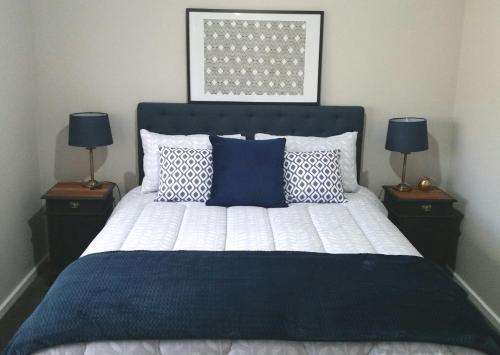 a bedroom with a bed with blue and white pillows at Kennedy House Euroa in Euroa