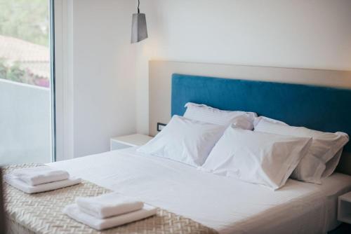 Una cama blanca con dos toallas encima. en Corner45 Apartments, en Kalamaki