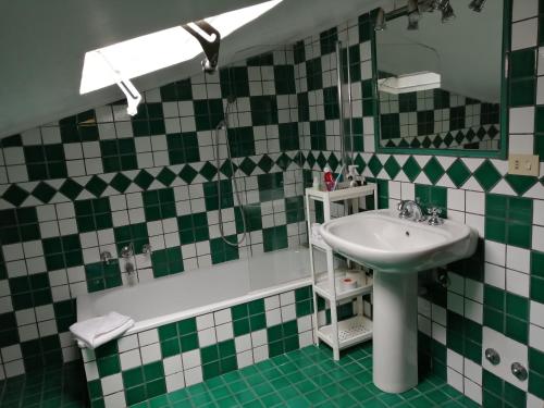 baño con lavabo y azulejos verdes y blancos en Residenza Monti, en Roma