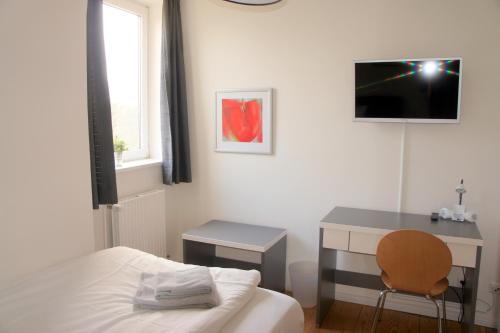 Schlafzimmer mit einem Bett, einem Schreibtisch und einem TV in der Unterkunft Apartment 1690 in Rendsburg