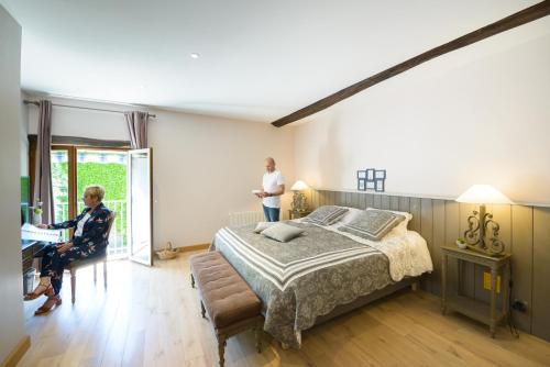 a woman sitting at a desk in a bedroom with a bed at La Closerie Saint-Vincent, chambres d'hôtes Amboise in Pocé-sur-Cisse