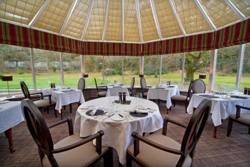 a restaurant with white tables and chairs and windows at Isle of Eriska Hotel Spa & Island in Benderloch