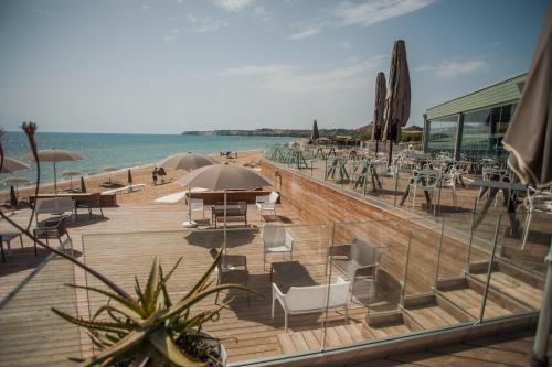 a wooden deck with chairs and umbrellas on a beach at Luna Minoica Suites and Apartments in Montallegro