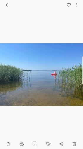 two pictures of the ocean with a red boat in the water at Namelis nr 1 Adelės sodyba in Sturmai