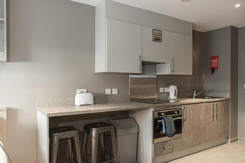 a kitchen with white cabinets and a counter with stools at For Students Only - Premium Accommodation at Eclipse Student Accommodation in Cardiff in Cardiff