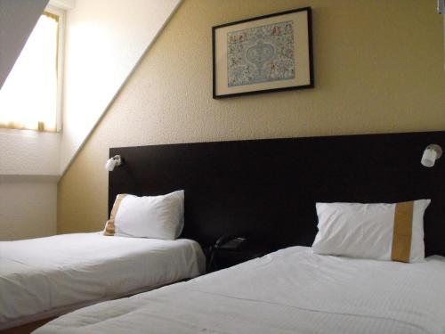 維桑堡的住宿－Hôtel d'Alsace，酒店客房设有两张床,墙上挂着一张照片。