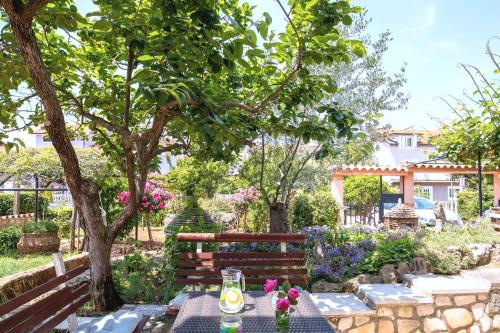 a garden with a table and a bench and flowers at Flora relax house, free parking in Peroj