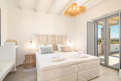 Biała sypialnia z dużym łóżkiem i balkonem w obiekcie Isalos Villas with private pool w mieście Naksos