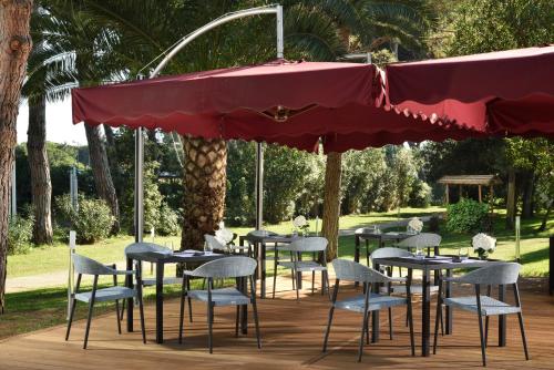 a row of tables and chairs under a red umbrella at Park Hotel Marinetta - Beach & Spa in Marina di Bibbona