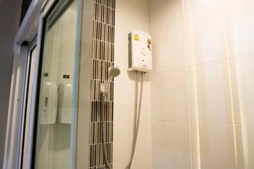 a shower in a bathroom with a phone on the wall at Zotel in Chiang Mai