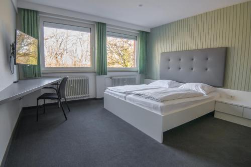 1 Schlafzimmer mit einem Bett, einem Schreibtisch und 2 Fenstern in der Unterkunft Adventure Campus in Treuchtlingen