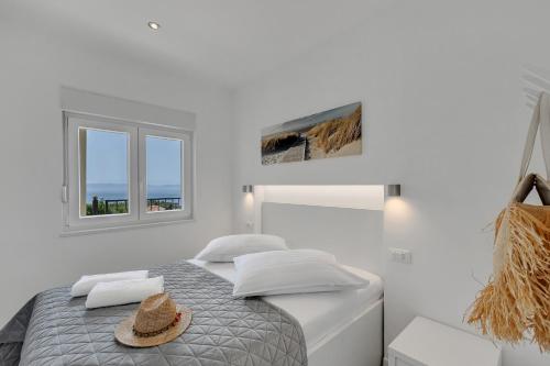 a white bedroom with a bed with a hat on it at Villa Pejic NEW, PENTHOUSE in Podgora