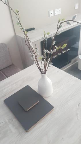 a white vase sitting on a table with a notebook at KINGDOM HOLIDAY PARK - Parrot in Millom