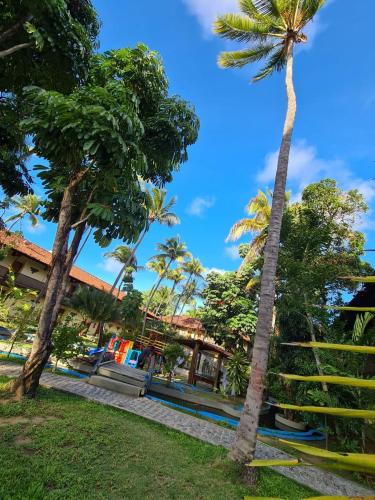 a group of palm trees in front of a building at Amoaras Resort in Maria Farinha