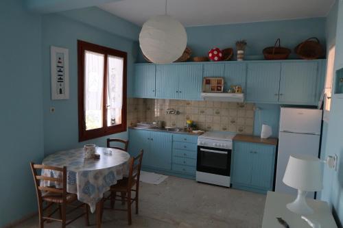 Akrogiali的住宿－Akrogiali Beach Apartments，厨房配有蓝色橱柜和桌椅
