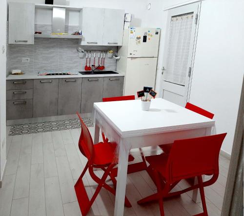 a kitchen with a white table and red chairs at B&b Casa Vita COMFORT HOME in Marconia