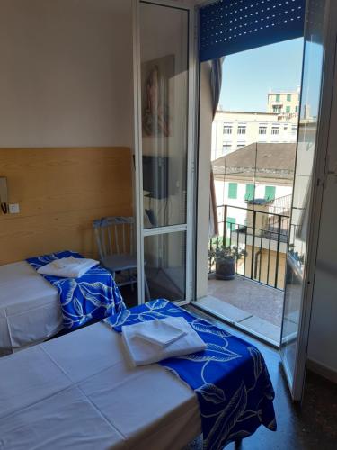 a bedroom with two beds and a large window at Hotel Guesthouse MASSENA in Genova