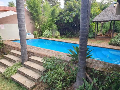 a swimming pool with stairs next to a house at Harties Honeymoon suite Mountain side - Hartbeespoort dam in Hartbeespoort