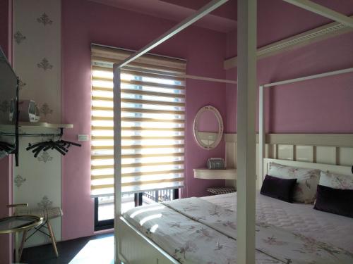 a bedroom with pink walls and a bed and a mirror at Teacher Cai Homeestay in Xiaoliuqiu