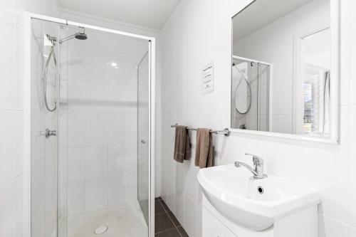 a white bathroom with a sink and a shower at Surf Beach Motel Coffs in Coffs Harbour