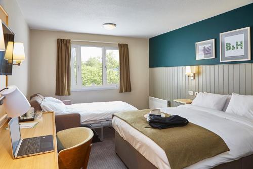 a hotel room with two beds and a desk with a laptop at Boat & Horses Inn in Oldham
