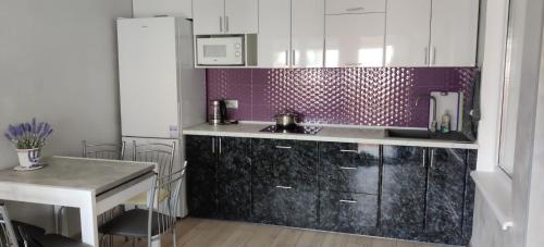 a kitchen with white cabinets and a purple wall at Будинок в Одесі біля моря 16 станція Фонтану in Odesa