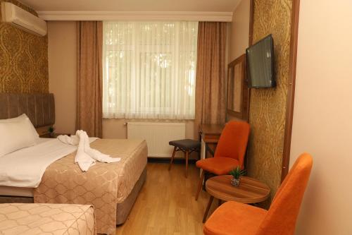a hotel room with a bed and a desk and a television at Buldum Otel in Ankara