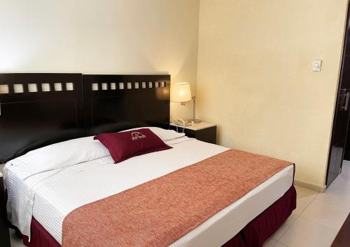 a bedroom with a large bed with a red pillow on it at Hotel Victoria Poza Rica by Brahma in Poza Rica de Hidalgo