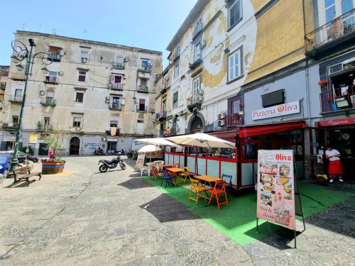 una strada con tavoli e ombrelloni di fronte agli edifici di ANDREA'S HOUSE a Napoli