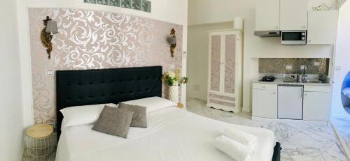 a bedroom with a large white bed and a kitchen at parisa suite in Rome