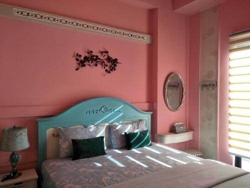 a bedroom with pink walls and a bed with a blue headboard at Teacher Cai Homeestay in Xiaoliuqiu