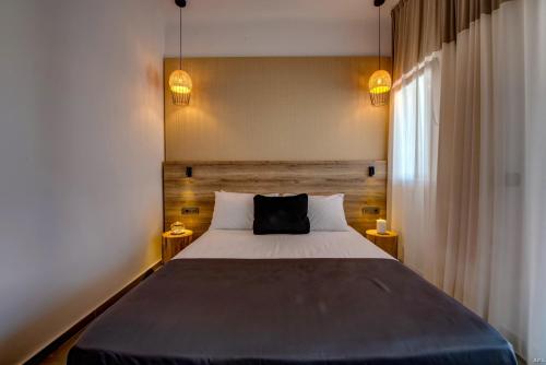 a bedroom with a large bed and two lamps at CASA DI PIETRA MYKONOS in Klouvas