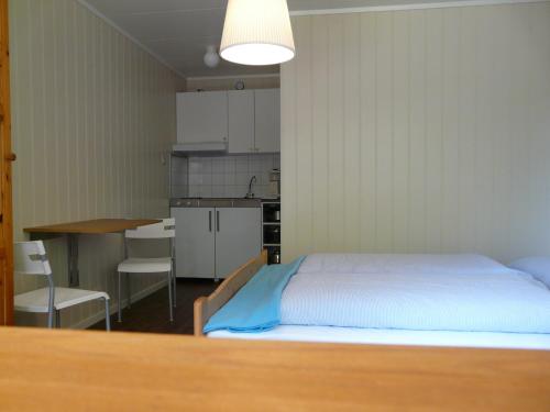 a bedroom with a bed and a table and a kitchen at Kvamsdal Pensjonat 2 in Eidfjord