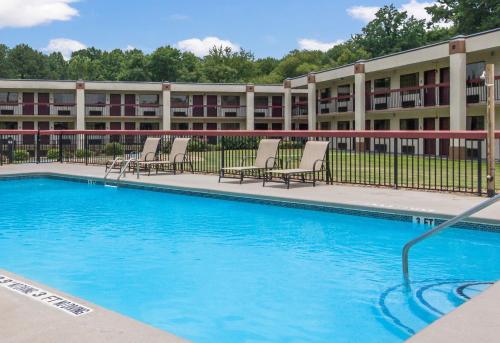 a swimming pool in front of a building with chairs at Red Roof Inn & Suites Commerce - Athens in Commerce