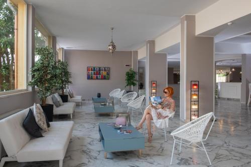 a woman sitting on a chair in a living room at Hotel President Sea Palace in Noto Marina