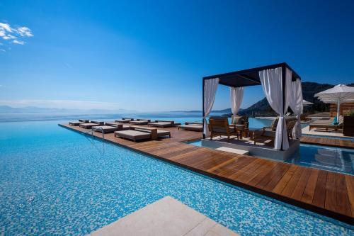 an infinity pool with chairs and a gazebo at Angsana Corfu Resort & Spa in Benitses