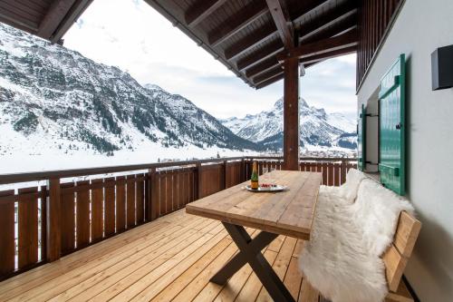 a wooden balcony with a table and a view of mountains at Bühlhof Appartements in Lech am Arlberg