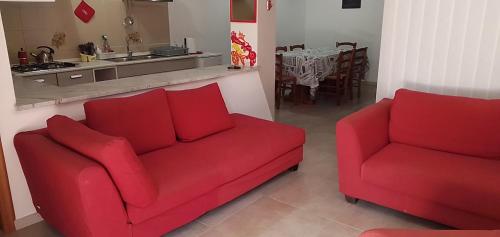 sala de estar con 2 sofás rojos y cocina en LaTavernapartment en Mascalucia