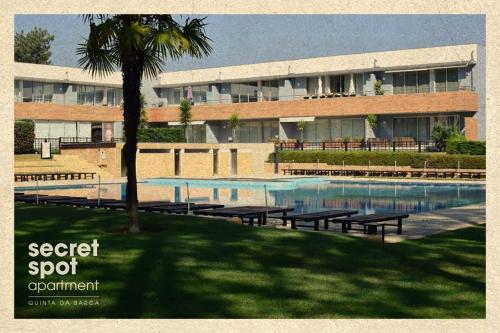 um edifício com uma piscina com bancos e uma palmeira em Secret Spot Apartment - Quinta da Barca em Esposende