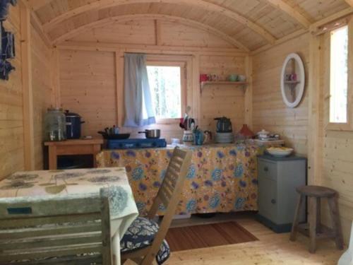 eine Küche mit einem Tisch in einer Holzhütte in der Unterkunft Lovely 2-Bed shepherds hut in a Forest in Sougères-en-Puisaye