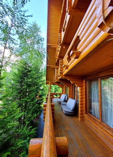 a wooden deck with couches on a house at Gostynniy Dvir in Forest Коттеджи in Migovo