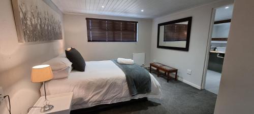 a bedroom with a bed and a table and two windows at DullVino First House in Dullstroom