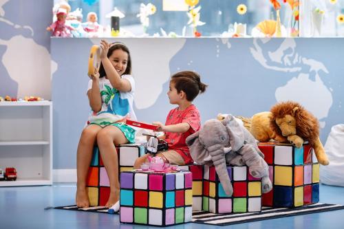 two children sitting on colorful boxes in a play room at Centara West Bay Hotel & Residences Doha in Doha