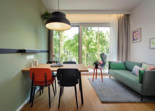 salon ze stołem i zieloną kanapą w obiekcie Zoku Vienna w Wiedniu