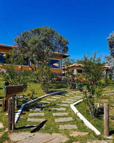 einen Garten mit einem Steinpfad vor einem Haus in der Unterkunft Pousada Eldorado Das Gerais in Carrancas