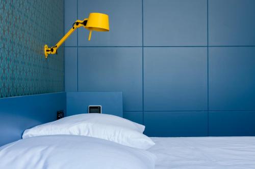 a blue bedroom with a bed with a lamp on it at De 6 Linden Boutique Hotel in Sluis