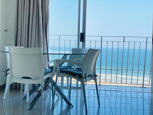 a dining room with a table and chairs and a view of the ocean at 86 windermere self catering apartments in Durban